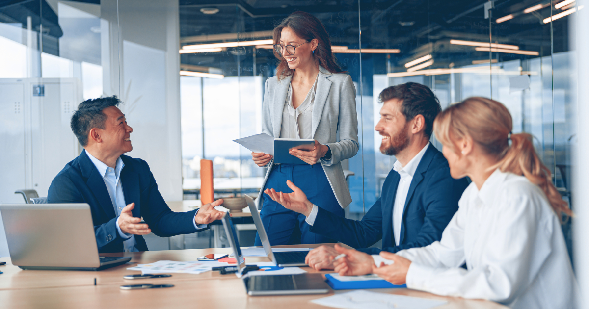 People in an office discuss business while laughing.