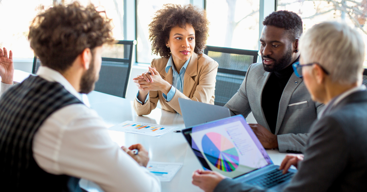 Business people sit around a table and discuss the changes to the consumer journey taking place while looking at charts.