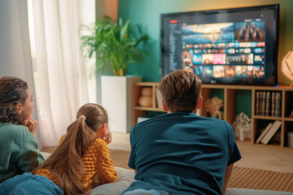 A family lays on the floor and watches streaming shows on the television.