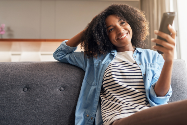 A young woman points her remote control at her smart TV and watches a streaming show. CTV completion rates now outperform other forms of viewing.
