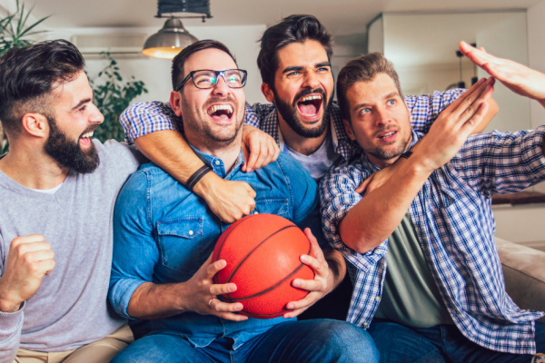 Friends sit around watching a basketball game streaming on their smart television.