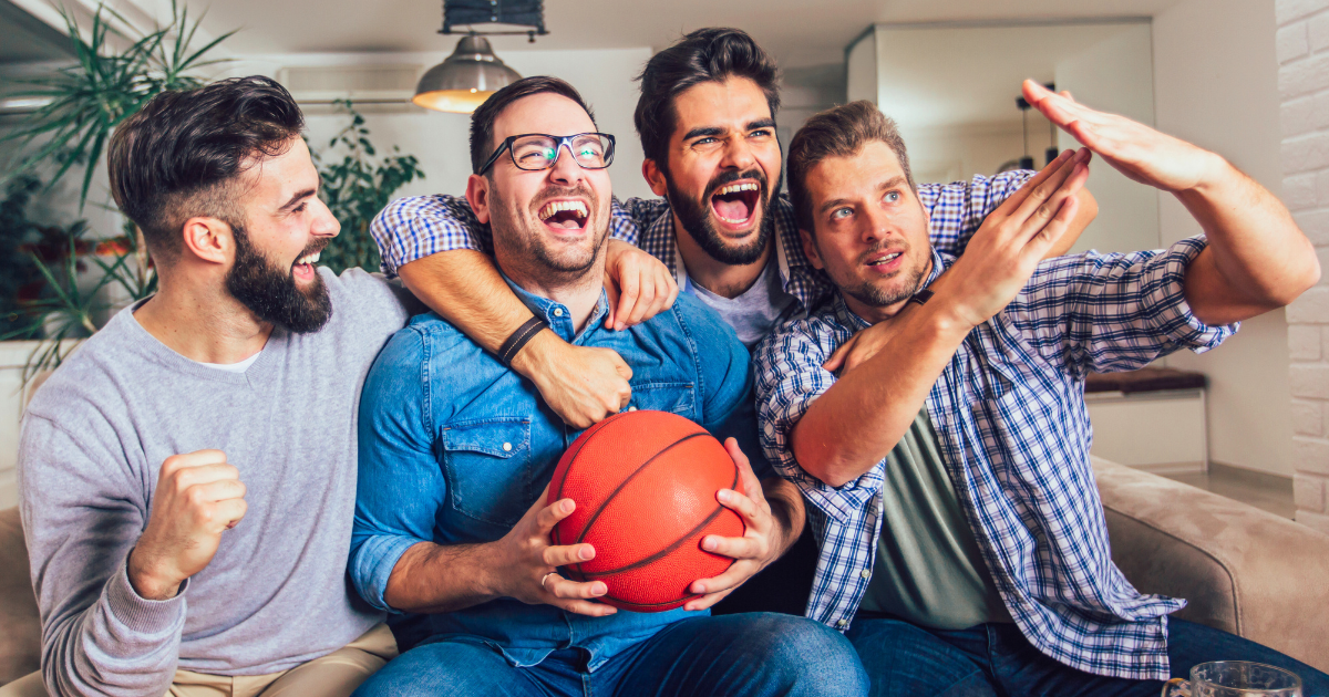 Friends sit around watching a basketball game streaming on their smart television.