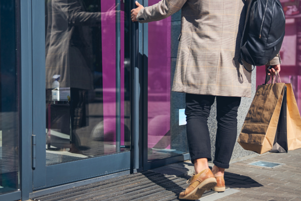 A man opens the door to a business while out shopping for the day.