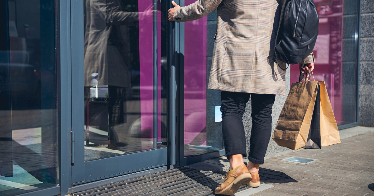 A man opens the door to a business while out shopping for the day.