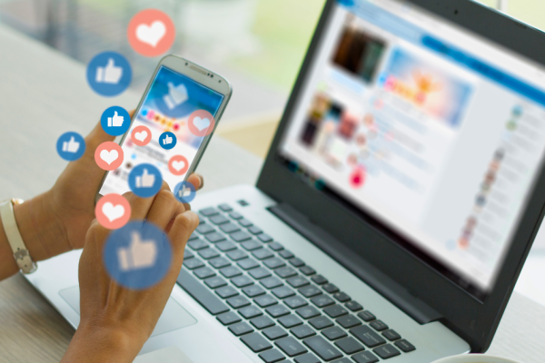 A female social media manager browses her phone and reacts to content while also browsing on her laptop