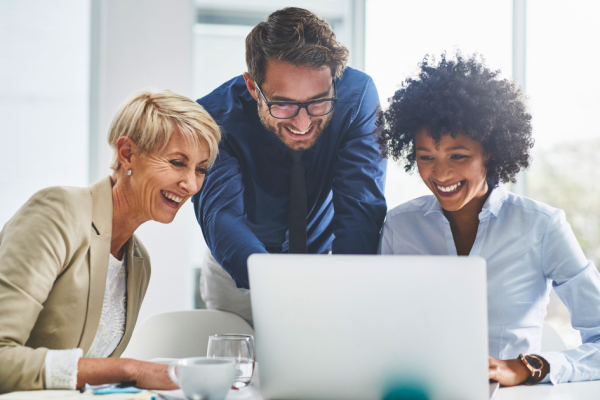 Business people gather around a laptop computer and discuss their GEO and AEO content strategy.