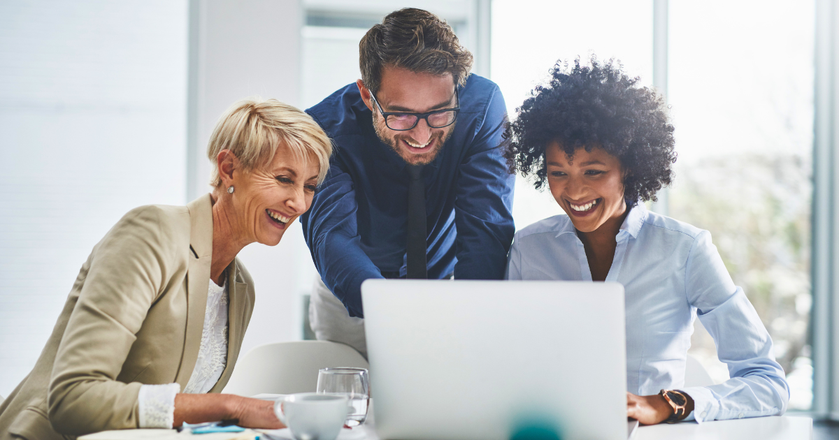 Business people gather around a laptop computer and discuss their GEO and AEO content strategy.