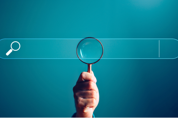 A hand holds a magnifying glass over a superimposed web search bar.