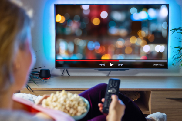 A woman pauses are streaming show while enjoying a bowl of popcorn.