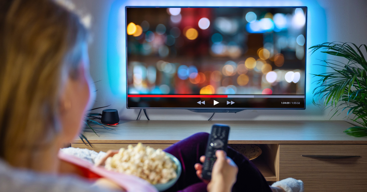 A woman pauses are streaming show while enjoying a bowl of popcorn.