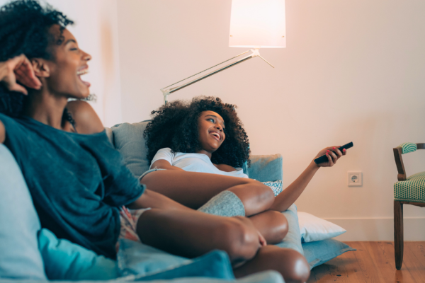 Two young, African American women voters browse television and watch broadcast tv ads.