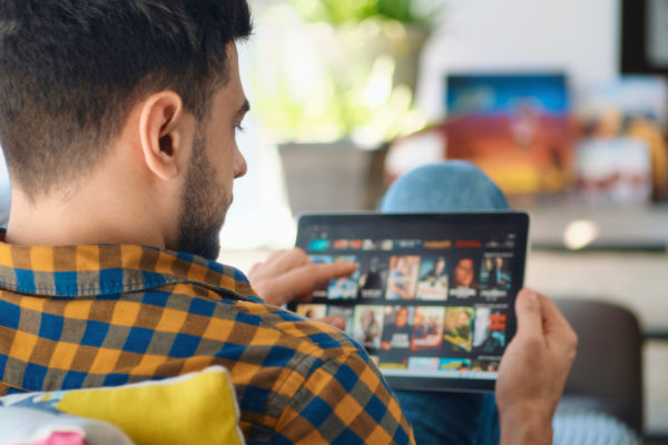A man looks at his tablet and browses streaming shows to watch.