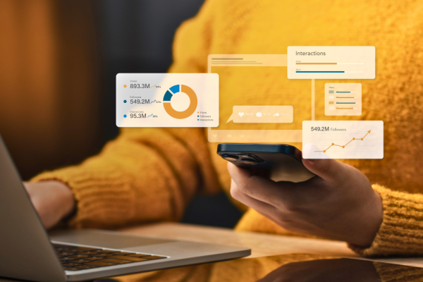 Woman in yellow shirt analyzing marketing metrics on laptop and mobile device