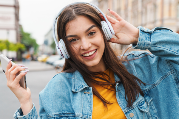 A young woman listens to a programmatic audio ad while streaming music on her mobile phone.
